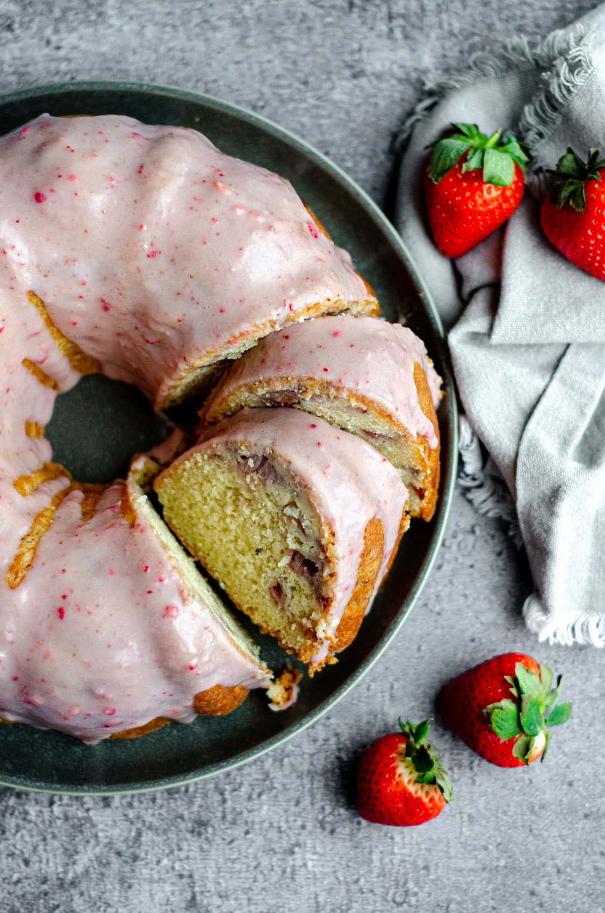 aerial photo of a strawberry bundt cake on a plate with some slices made into it
