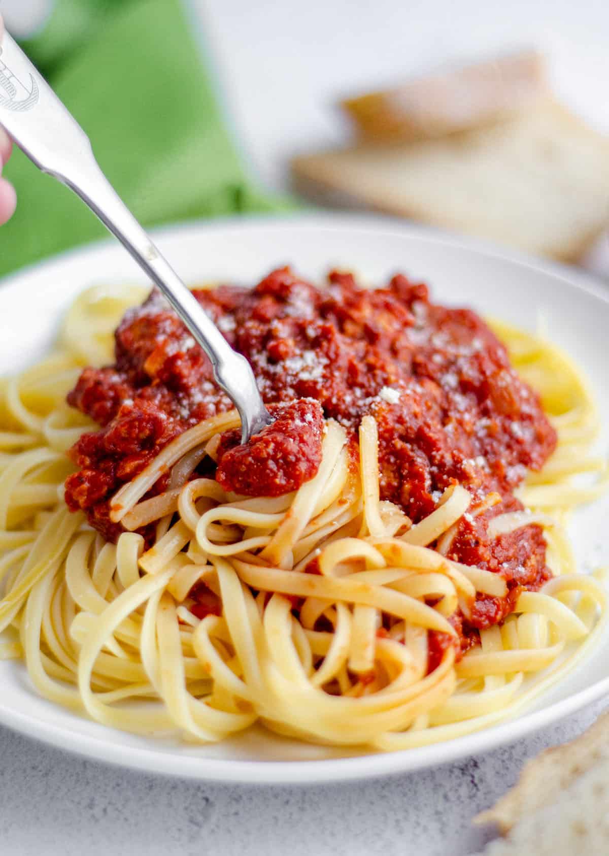 plate of spaghetti with meat sauce with a fork twirling some pasta