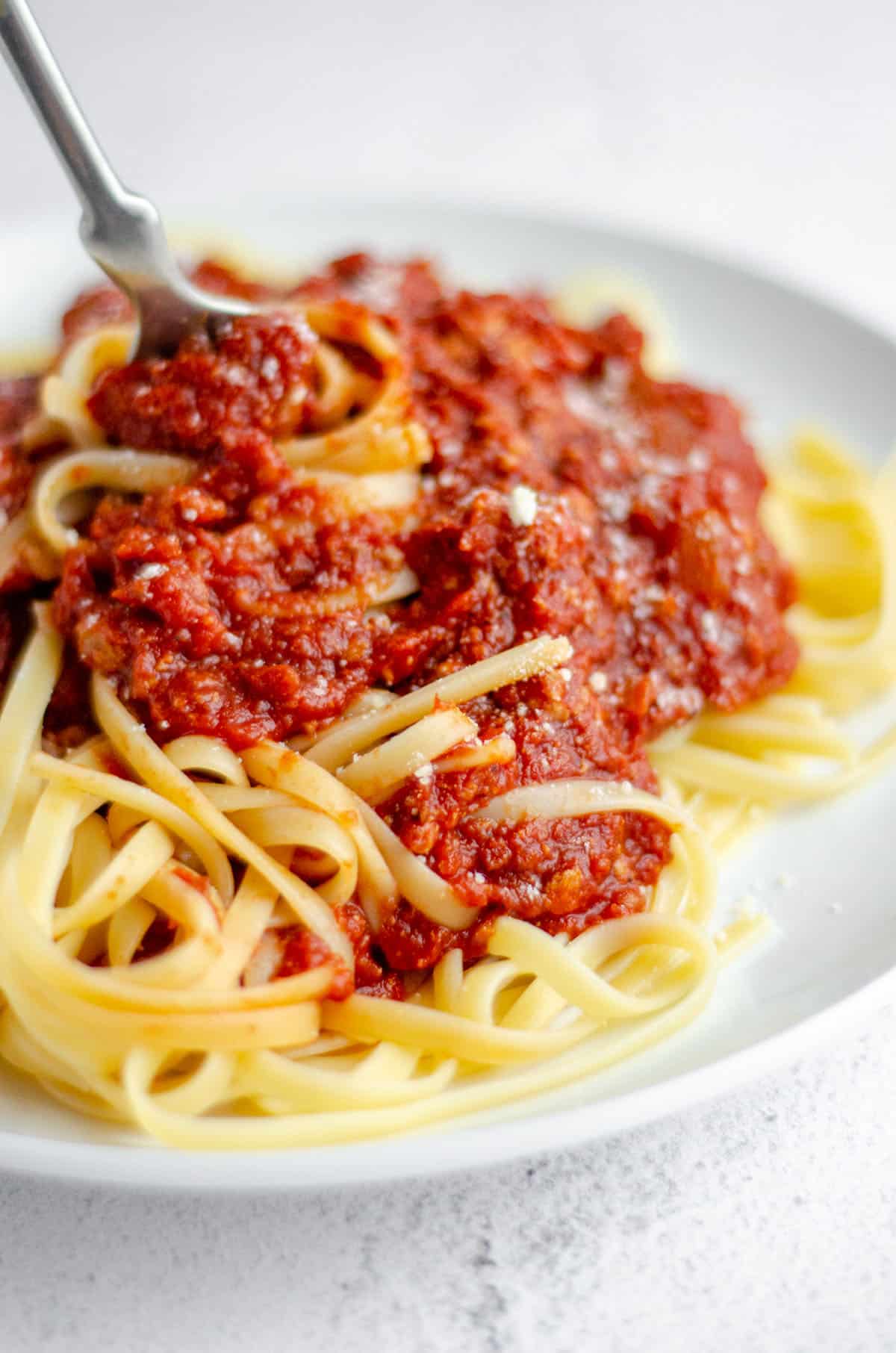 plate of spaghetti with meat sauce with a fork twirling some pasta
