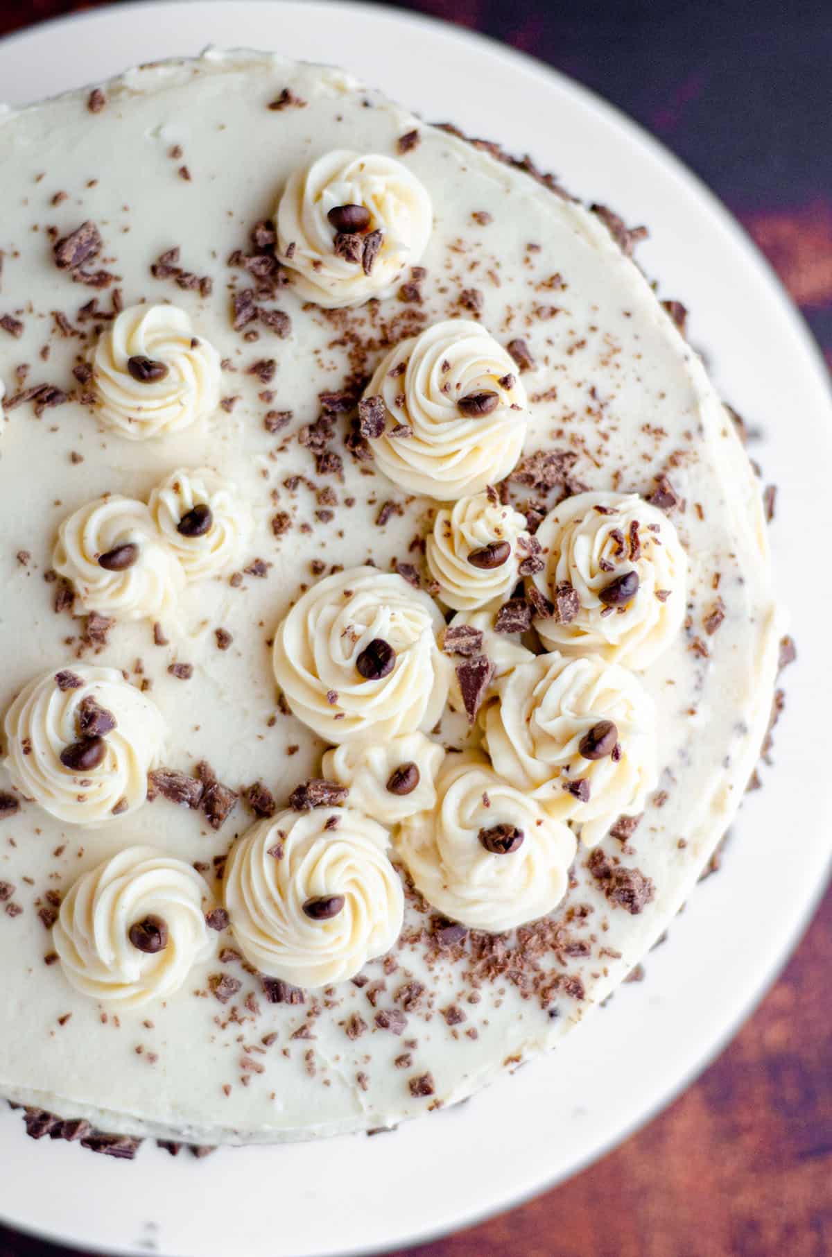 aerial photo of mocha cake with coffee buttercream decorated with chunks of chocolate and coffee beans