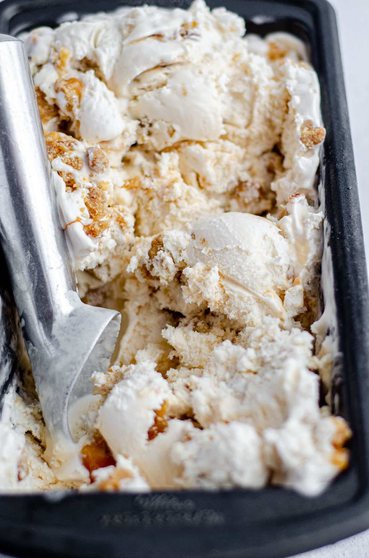 homemadee praline ice cream in a loaf pan with an ice cream scoop