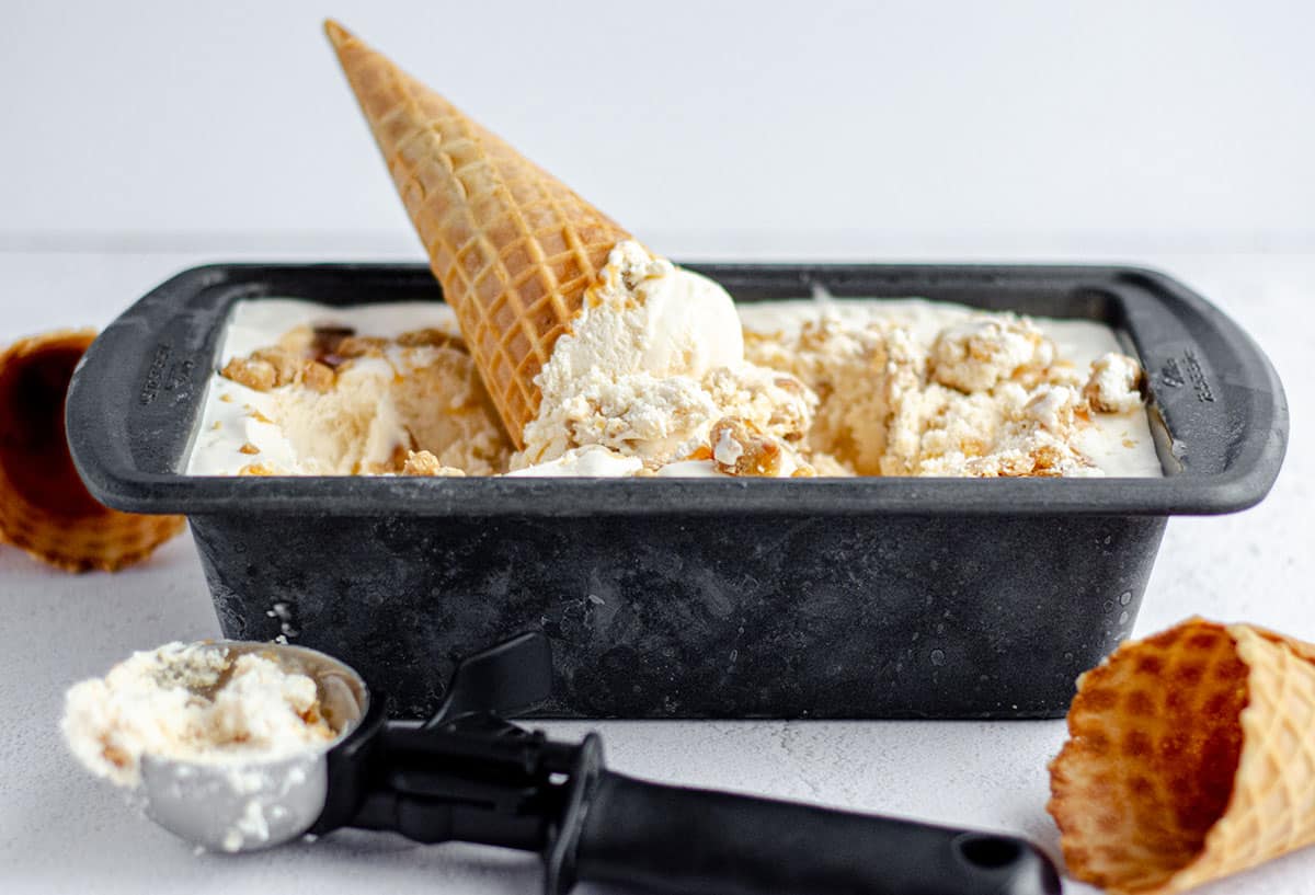homemade praline ice cream in a loaf pan with an ice cream cone stuck in it