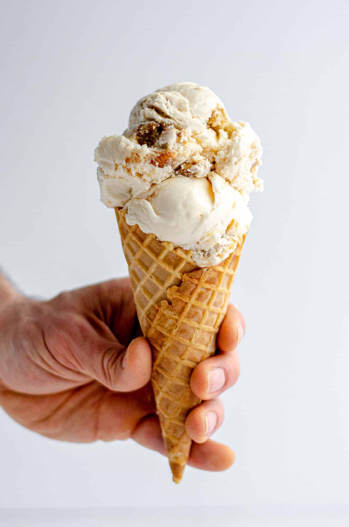 hand holding an ice cream cone filled with praline ice cream