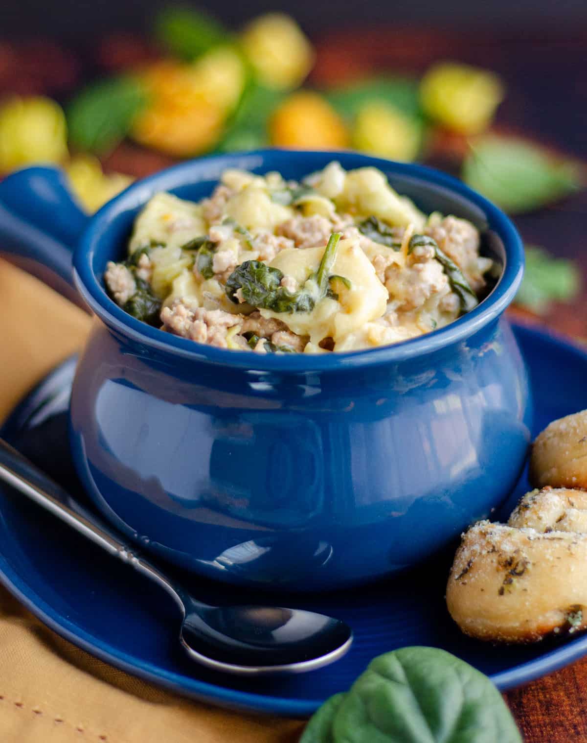 sausage tortellini soup in a blue bowl