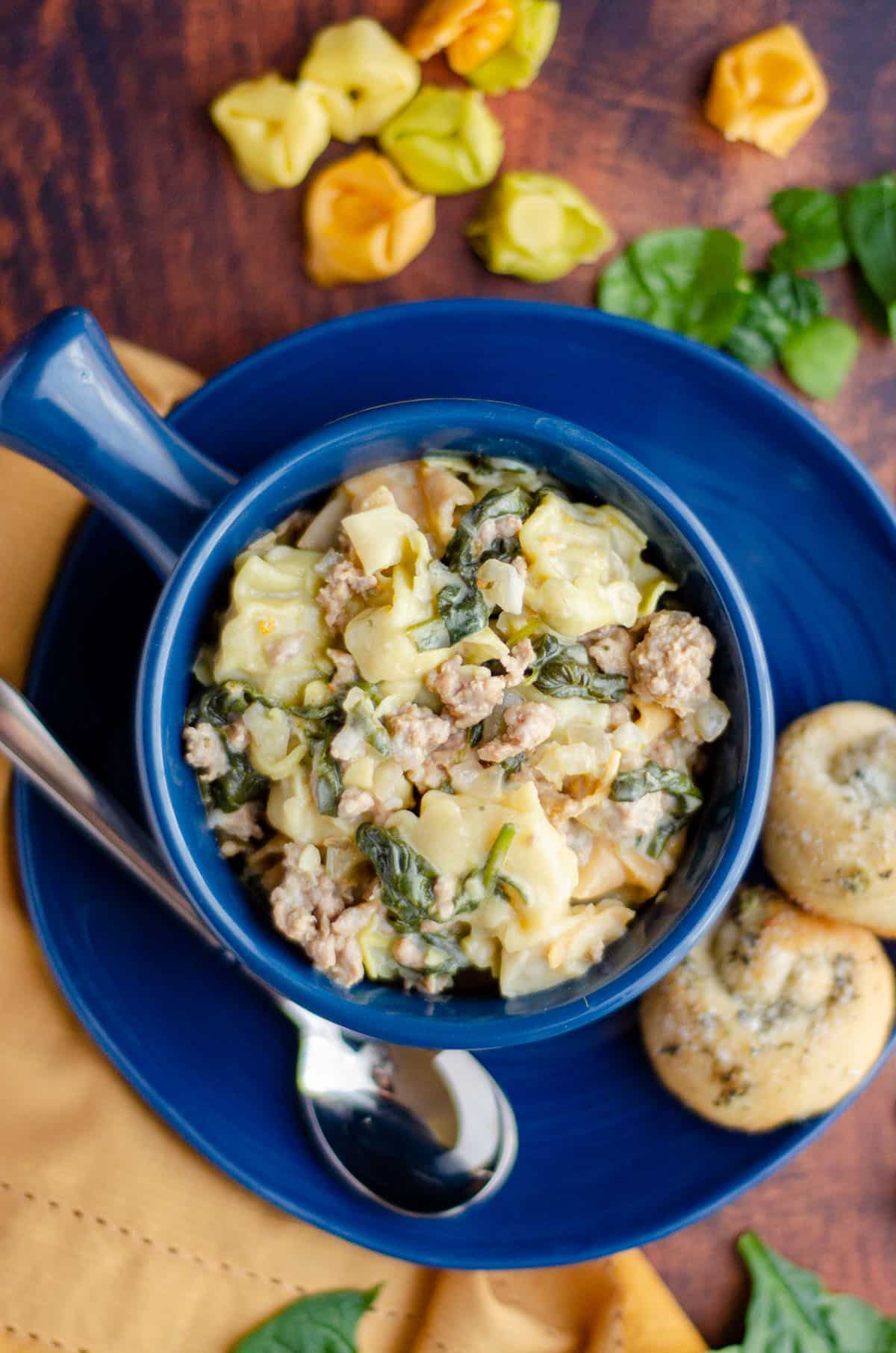 aerial photo of sausage tortellini soup in a blue bowl