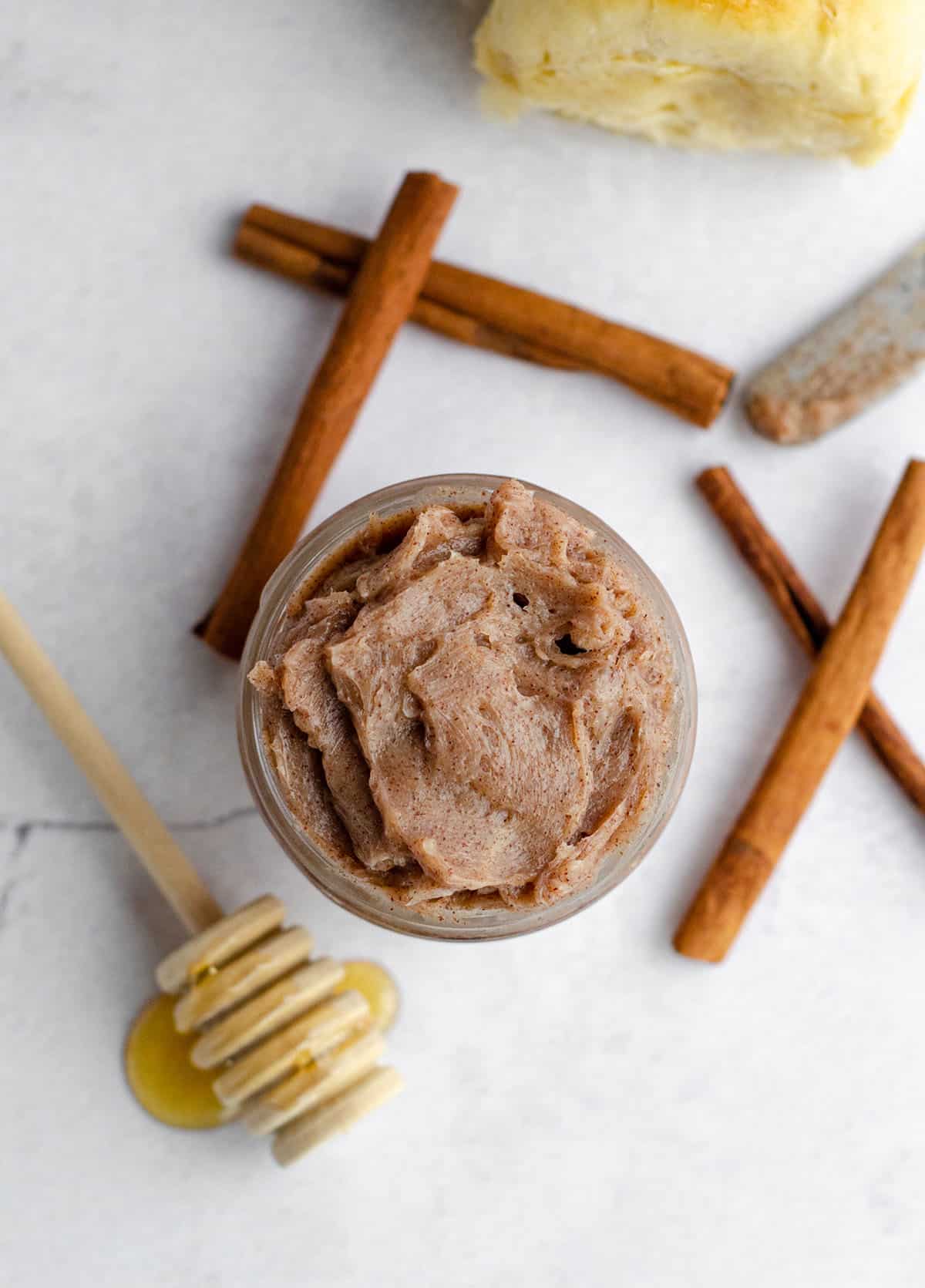 aerial photo of cinnamon honey butter in a jar with cinnamon sticks and a honey dipper 