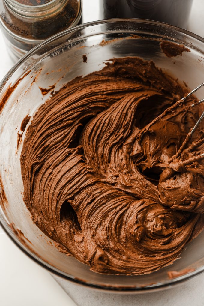 Aerial photo of someone beating mocha frosting in a bowl with electric beaters.
