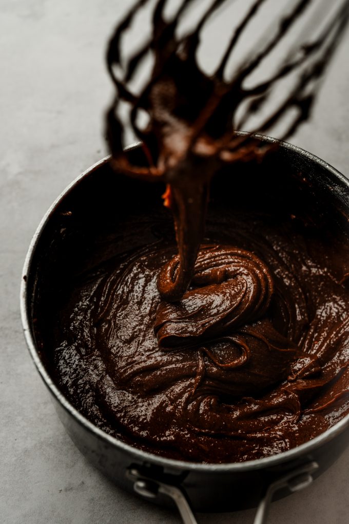 Aerial photo of a saucepan of coffee brownie batter with a whisk in it.