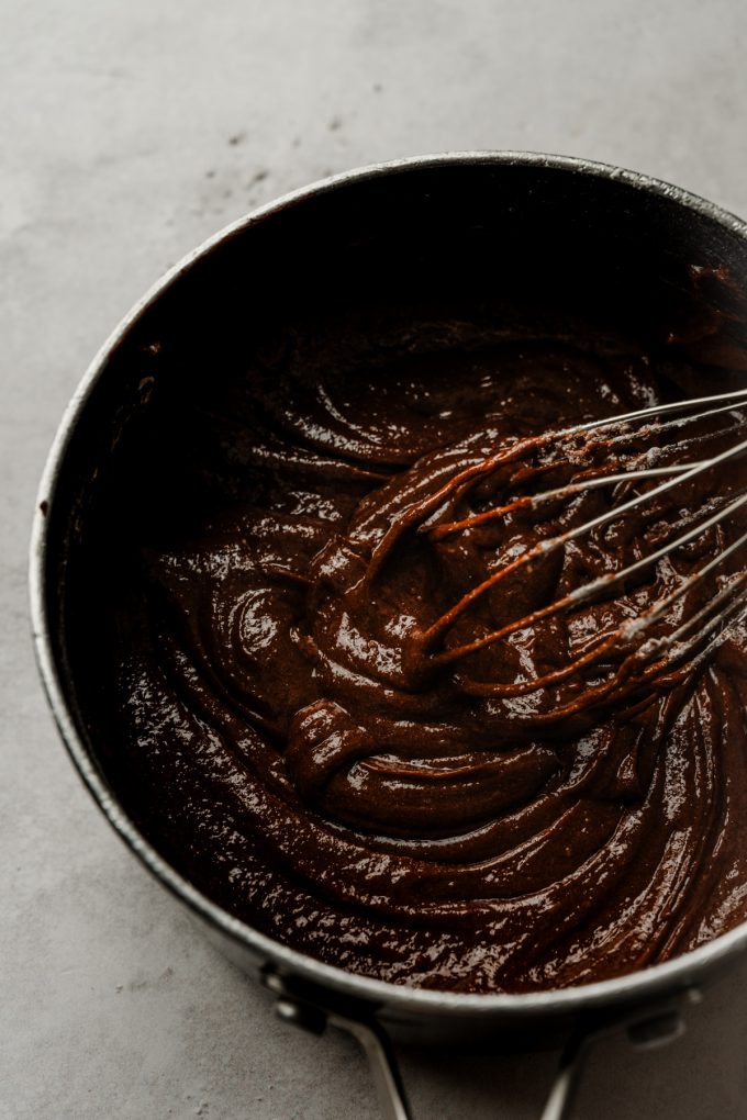 Aerial photo of a saucepan of coffee brownie batter with a whisk in it.