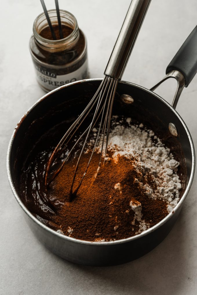 Someone is whisking the dry ingredients into a saucepan of the base for coffee brownies.