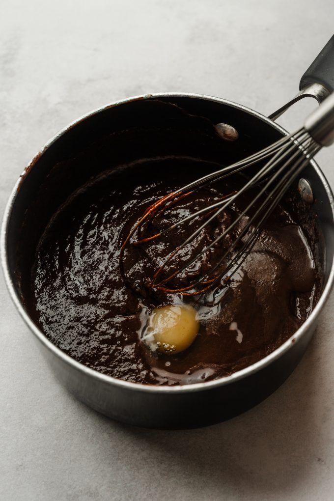 Someone is whisking eggs into a saucepan of the base for brownies.