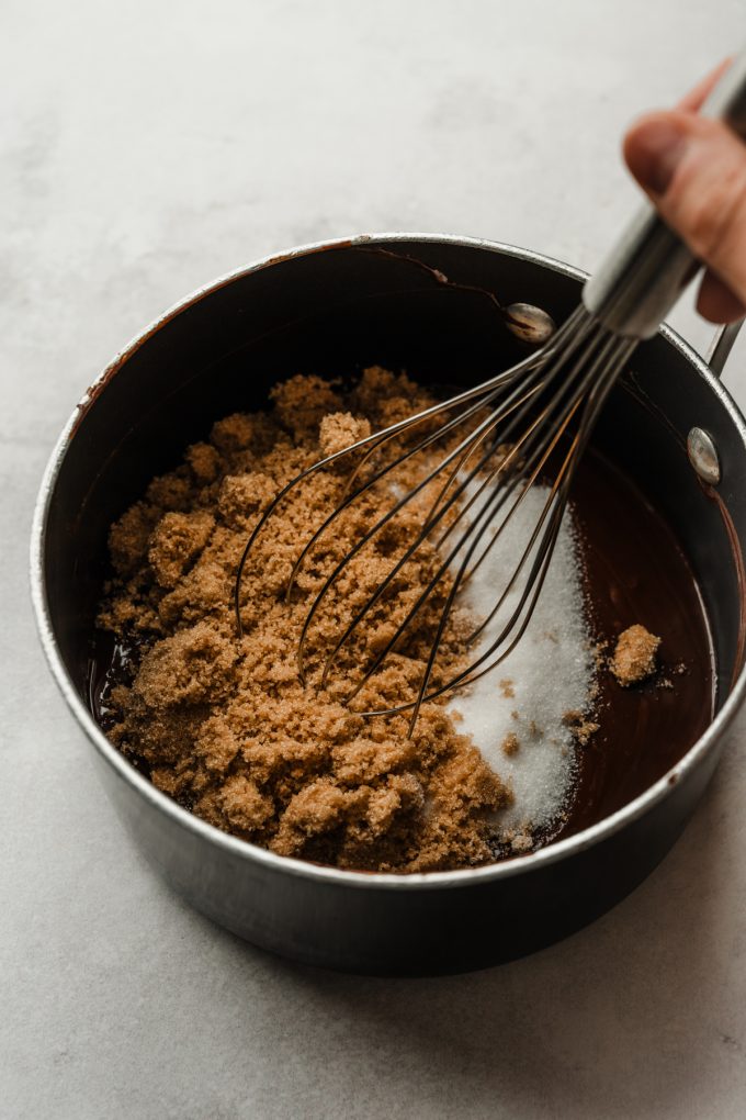 Someone is whisking sugars into a saucepan of the base for brownies.