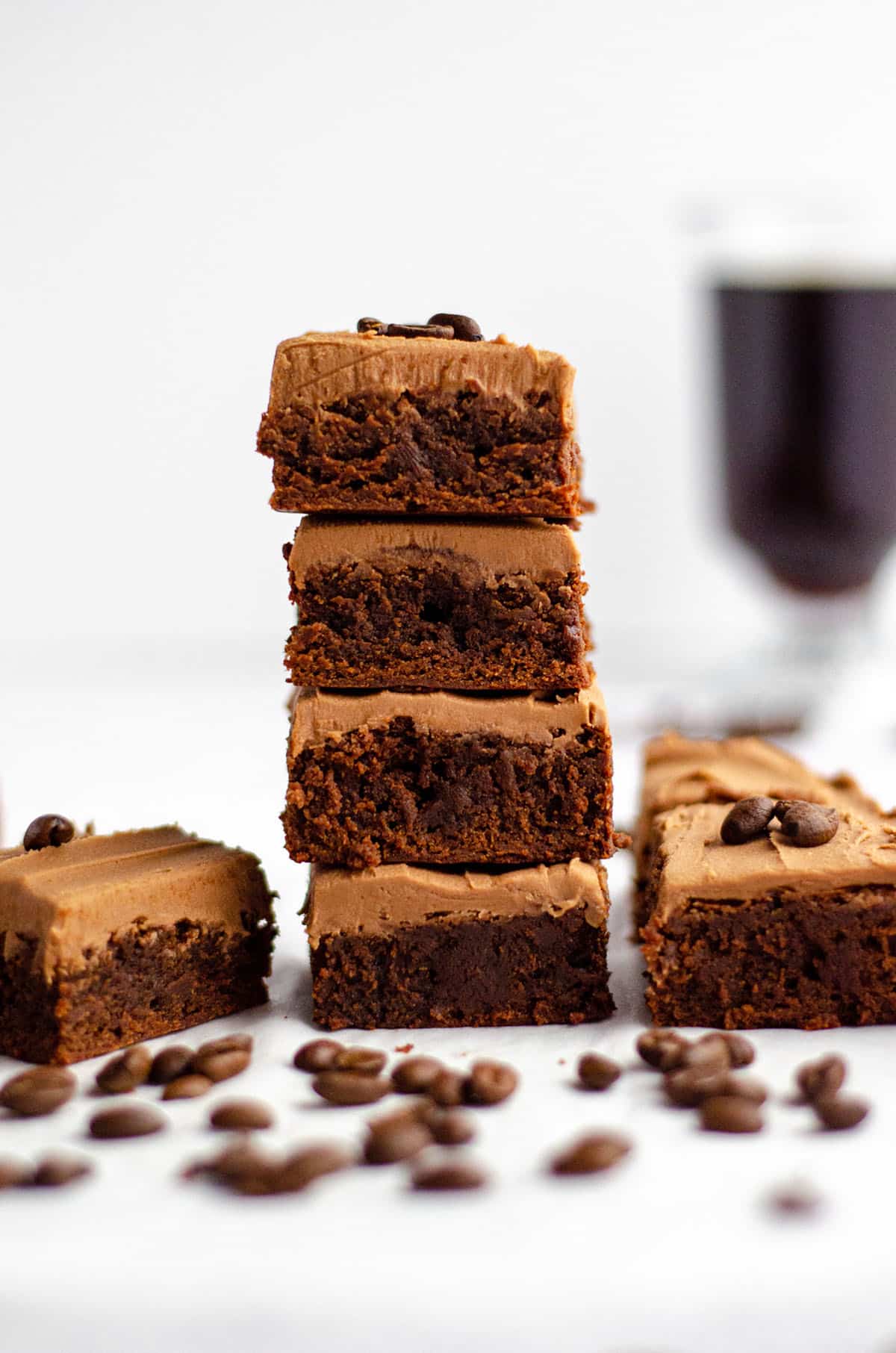 stack of coffee brownies with mocha frosting and a cup of coffee in the background