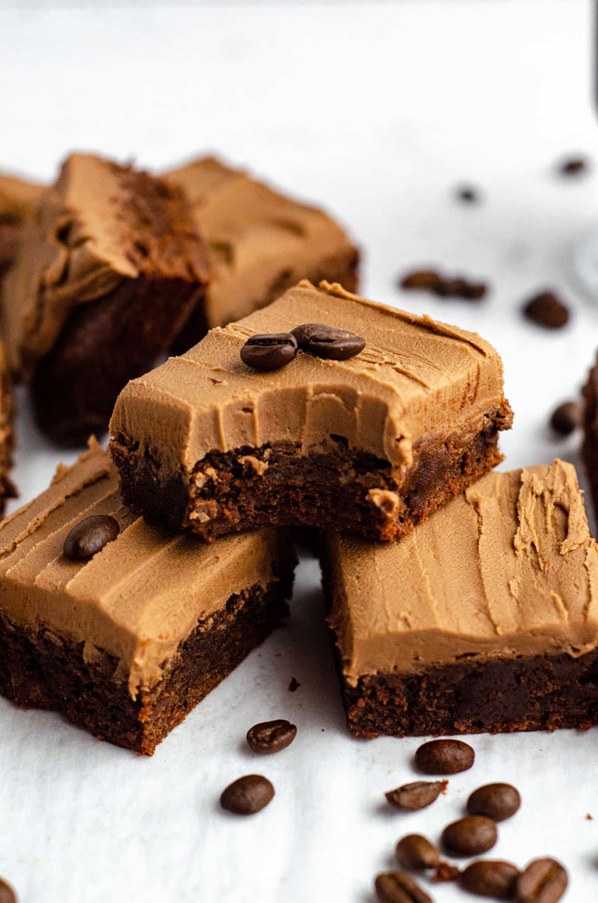 stack of coffee brownies with mocha frosting-- the top brownie has a bite taken out of it