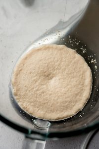 Yeast and milk in the bowl of a stand mixer after the yeast has proofed.