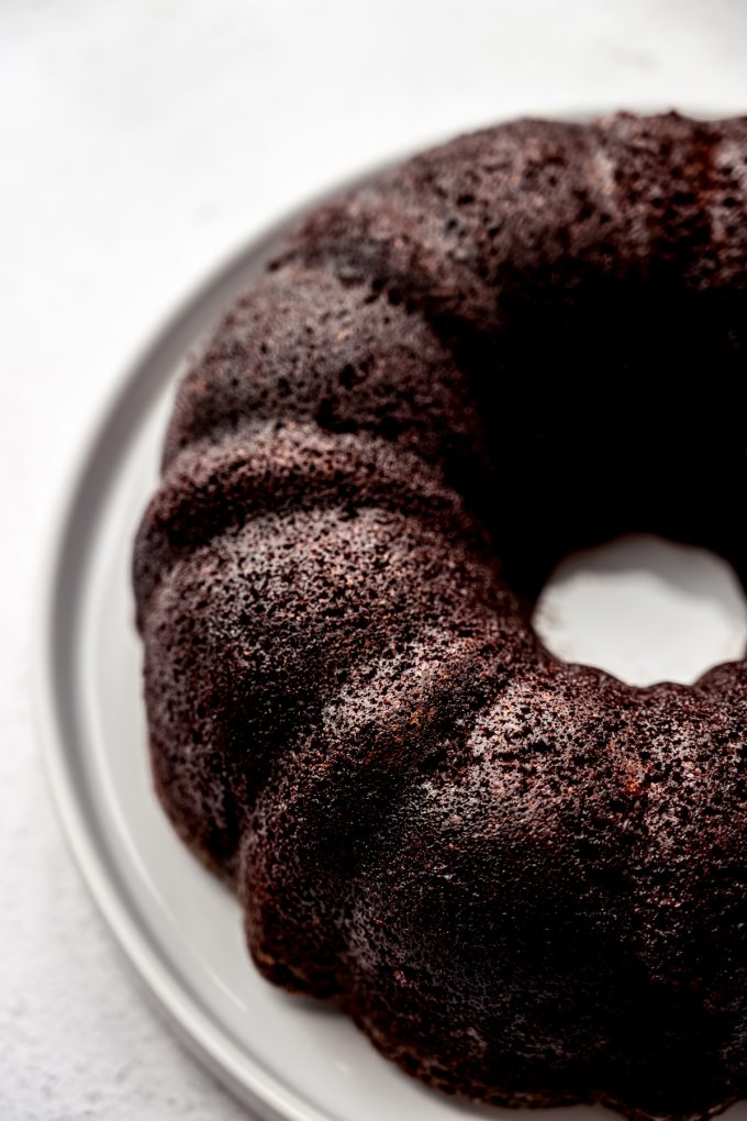 A chocolate Bundt cake on a plate before it has icing on it.