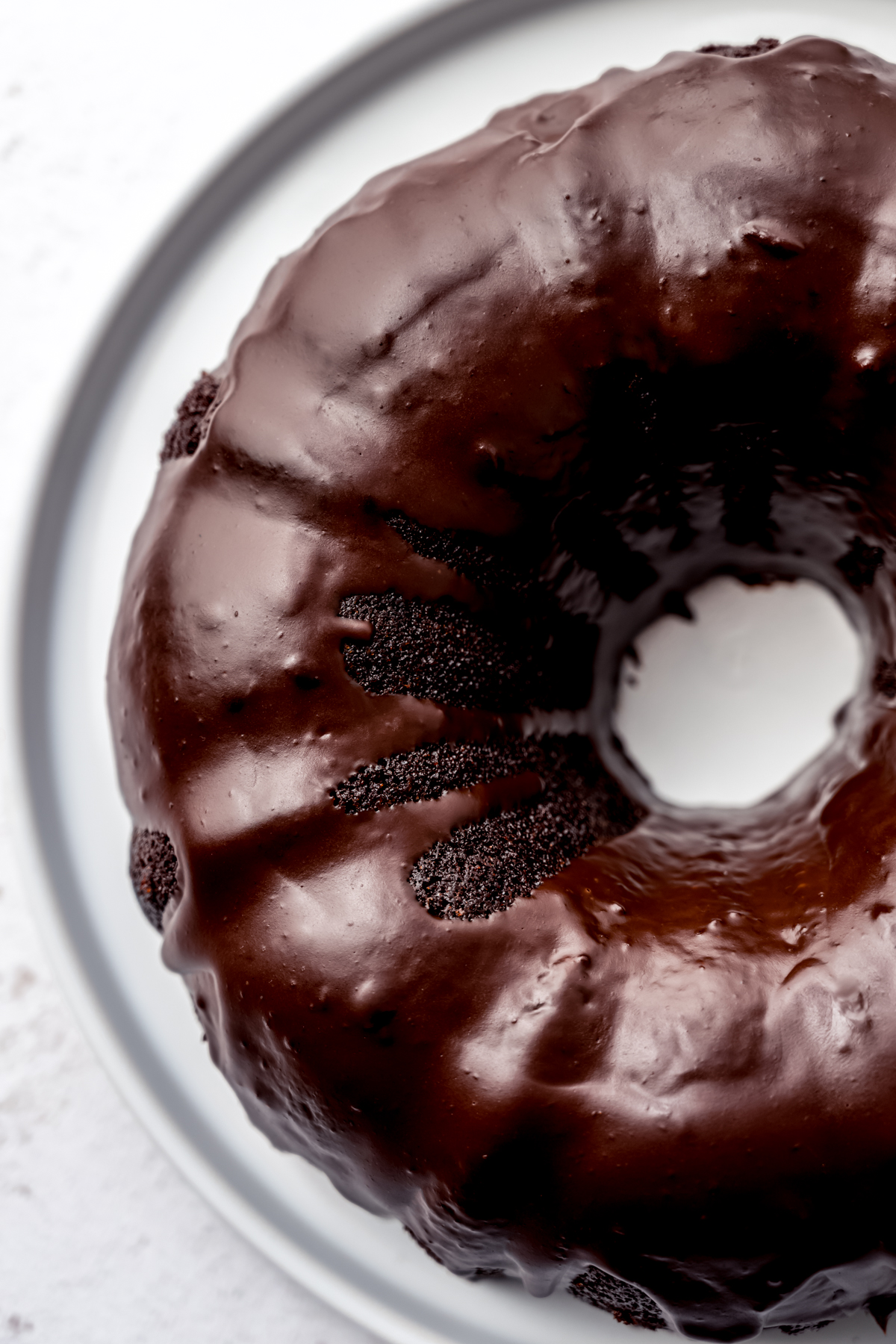 Aerial photo of a chocolate Bundt cake with chocolate ganache on a plate.