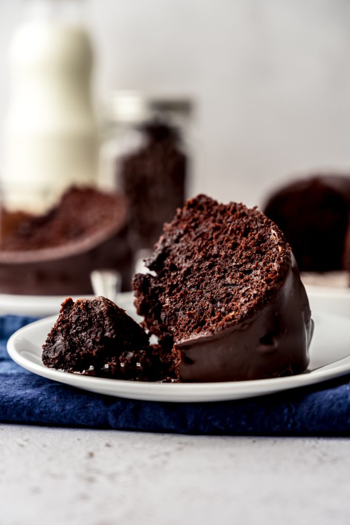 A slice of chocolate Bundt cake on a plate with a fork holding a bite of the cake.