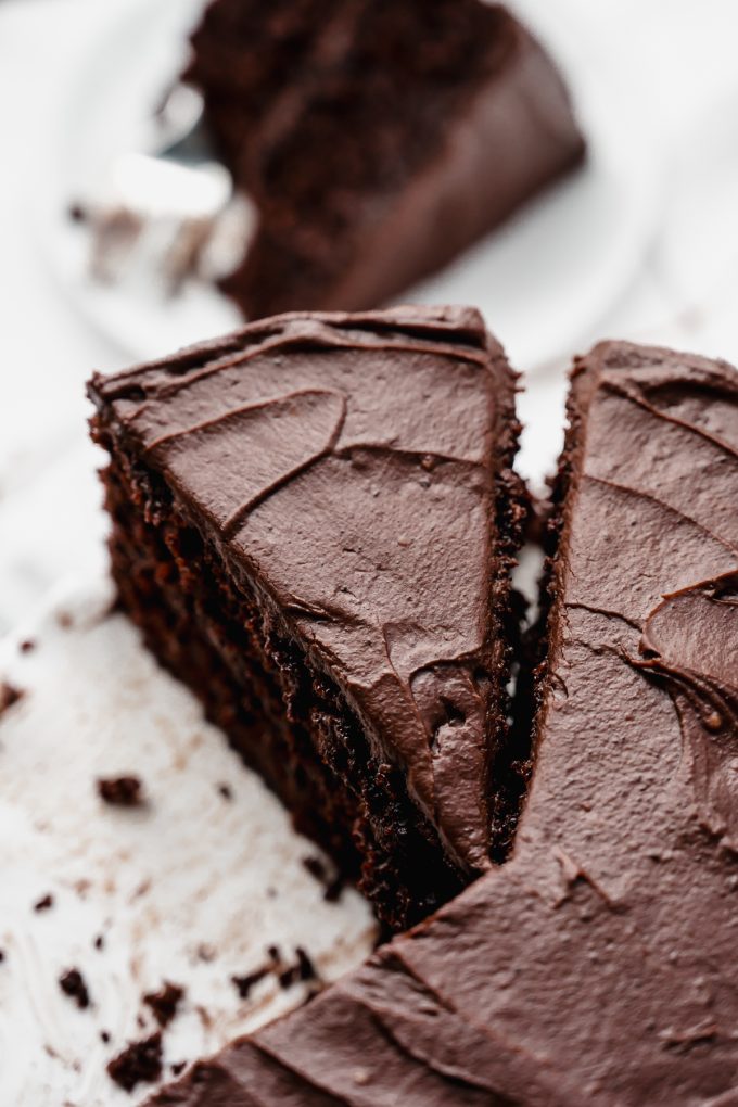 A chocolate cake on a stand that has been sliced.