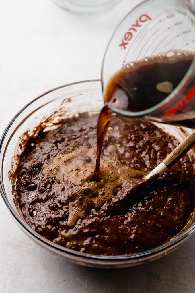 Someone is pouring boiling coffee into a bowl of chocolate cake batter.
