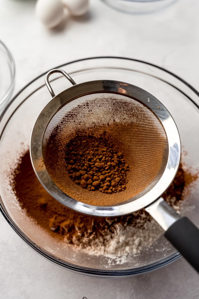 Someone is sifting cocoa powder into dry ingredients.