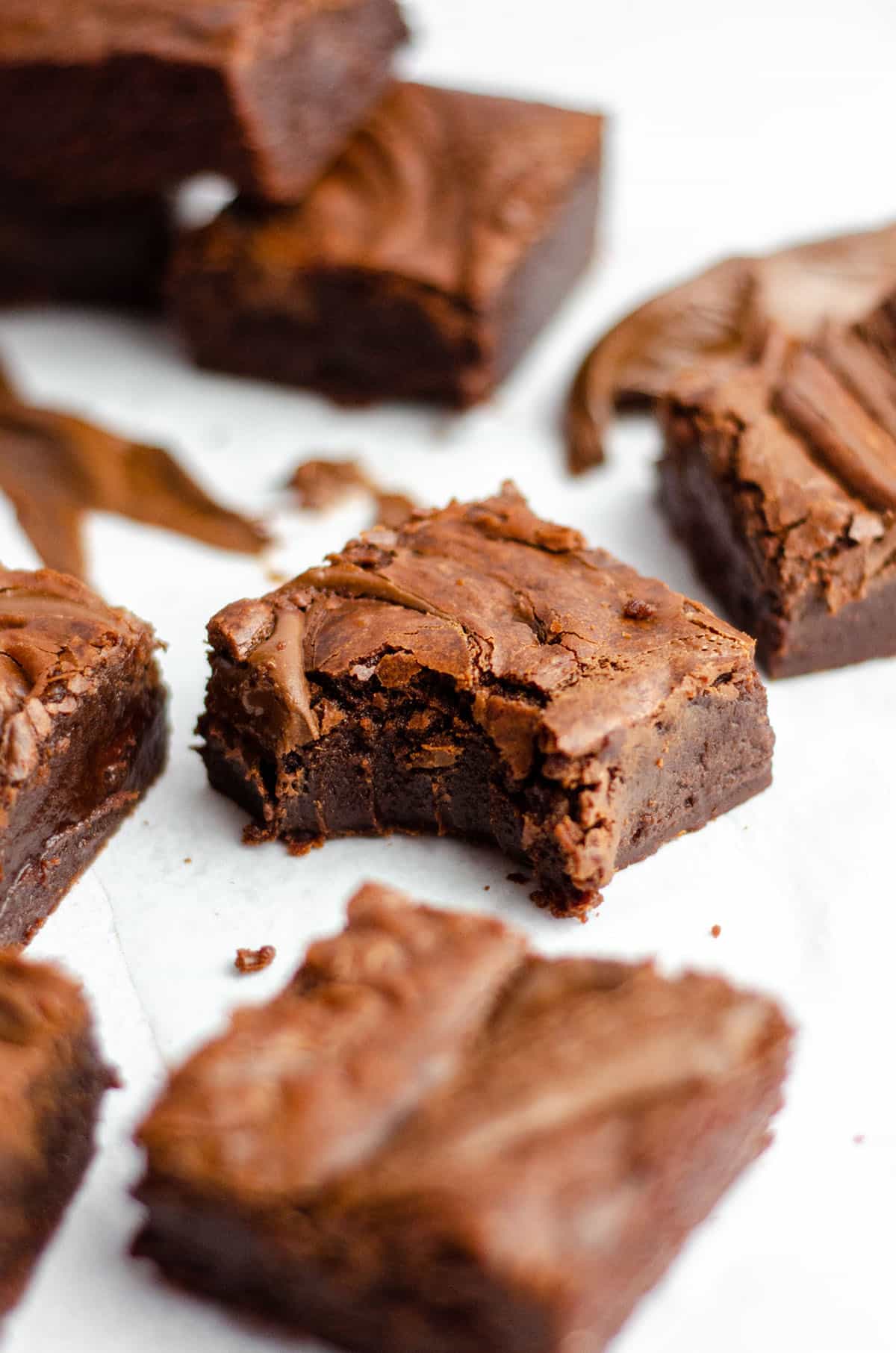 fudgy nutella brownies on a white surface and one with a bite taken out of it