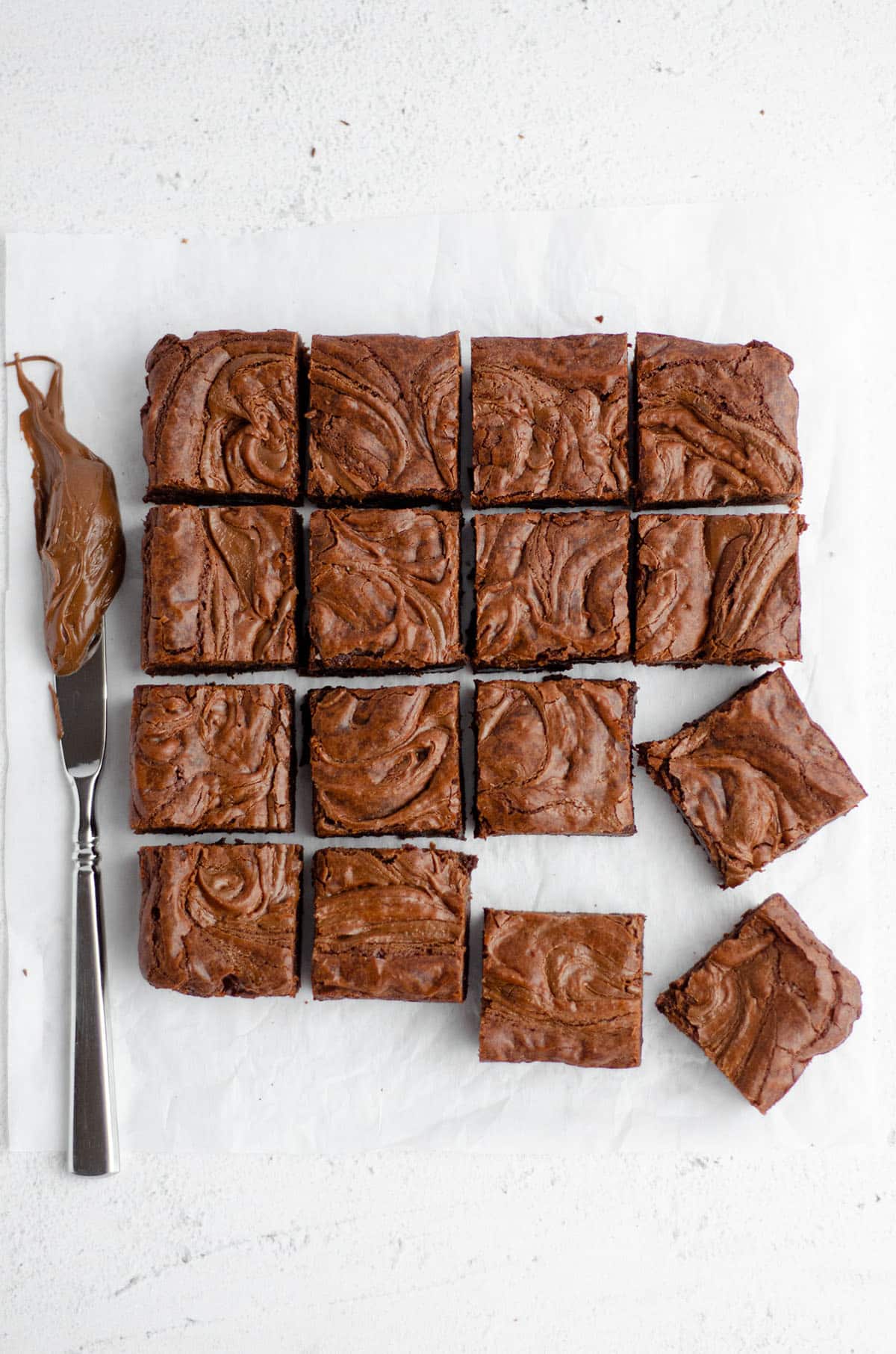 aerial photo of sliced fudgy nutella brownies with a knife with nutella on it next to them