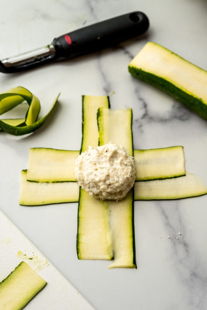Zucchini layers made into a T shape with a dollop of ricotta filling to make zucchini ravioli.