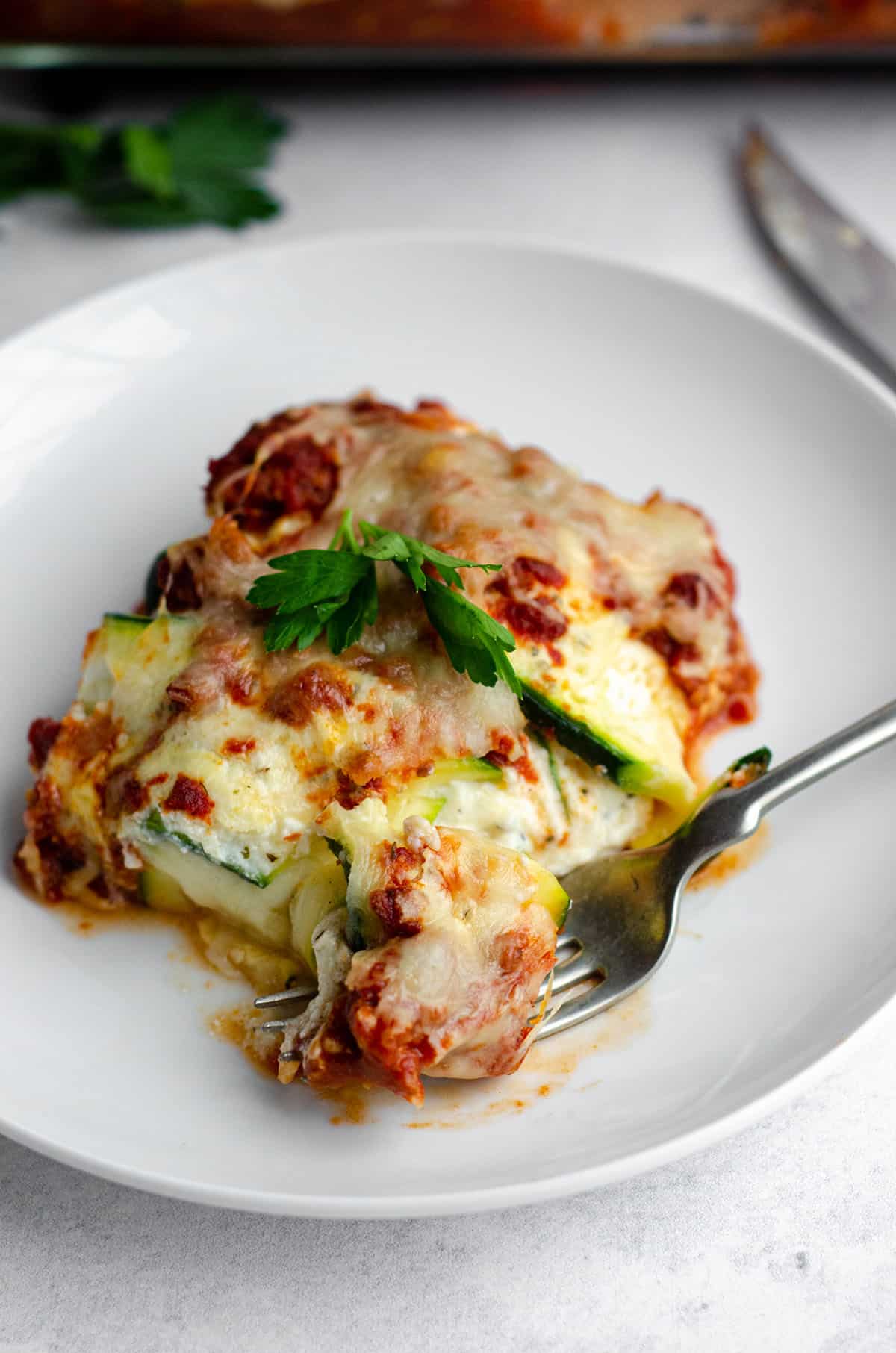 zucchini ravioli sitting on a plate with a fork full of a bite