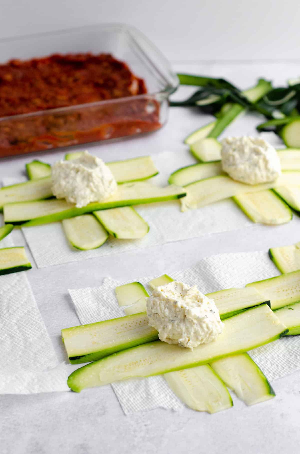 zucchini strips with a dollop of filling on the intersection to make zucchini ravioli