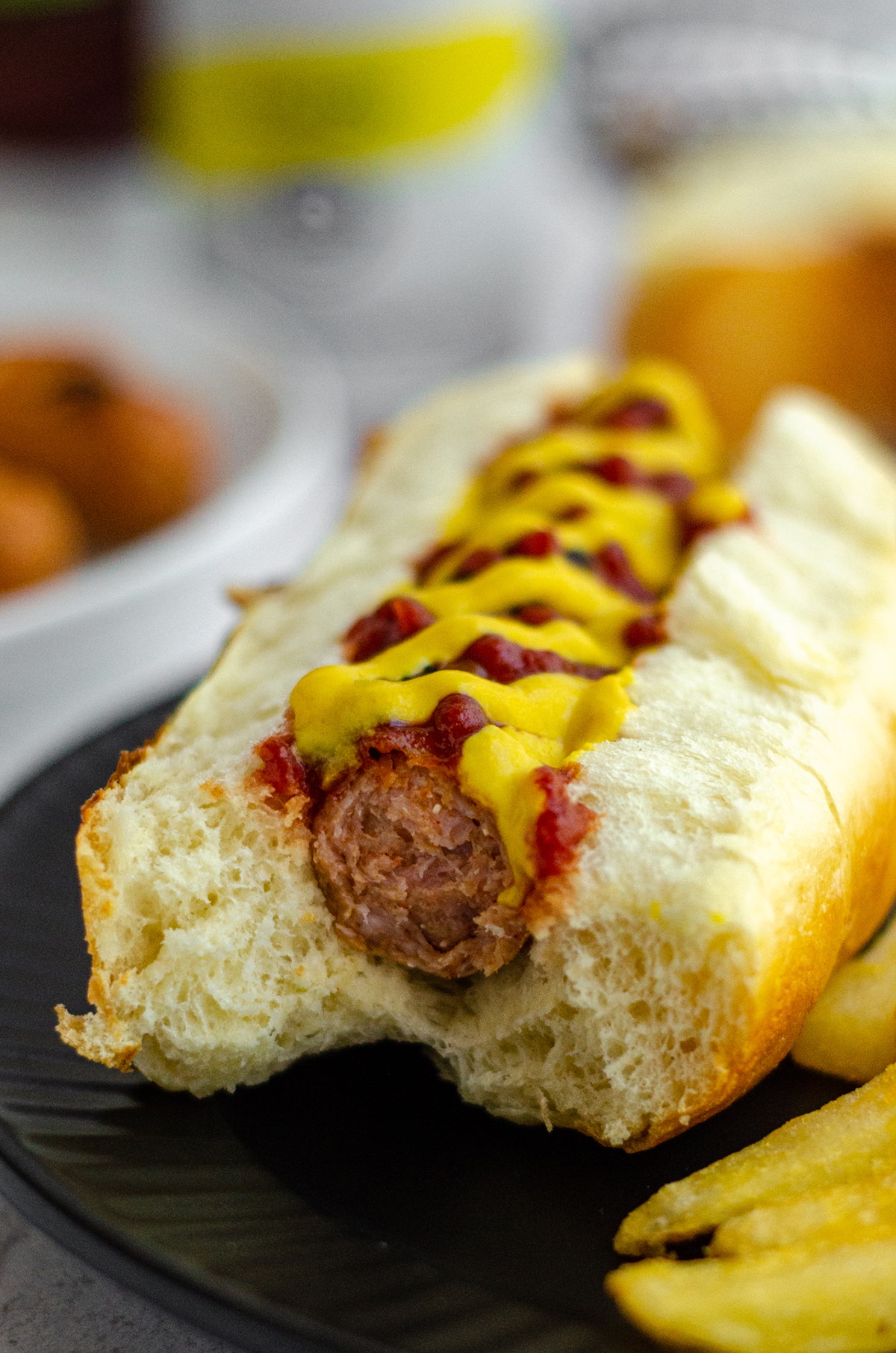 hot dog in a homemade hot dog bun with ketchup and mustard and a bite taken out of it