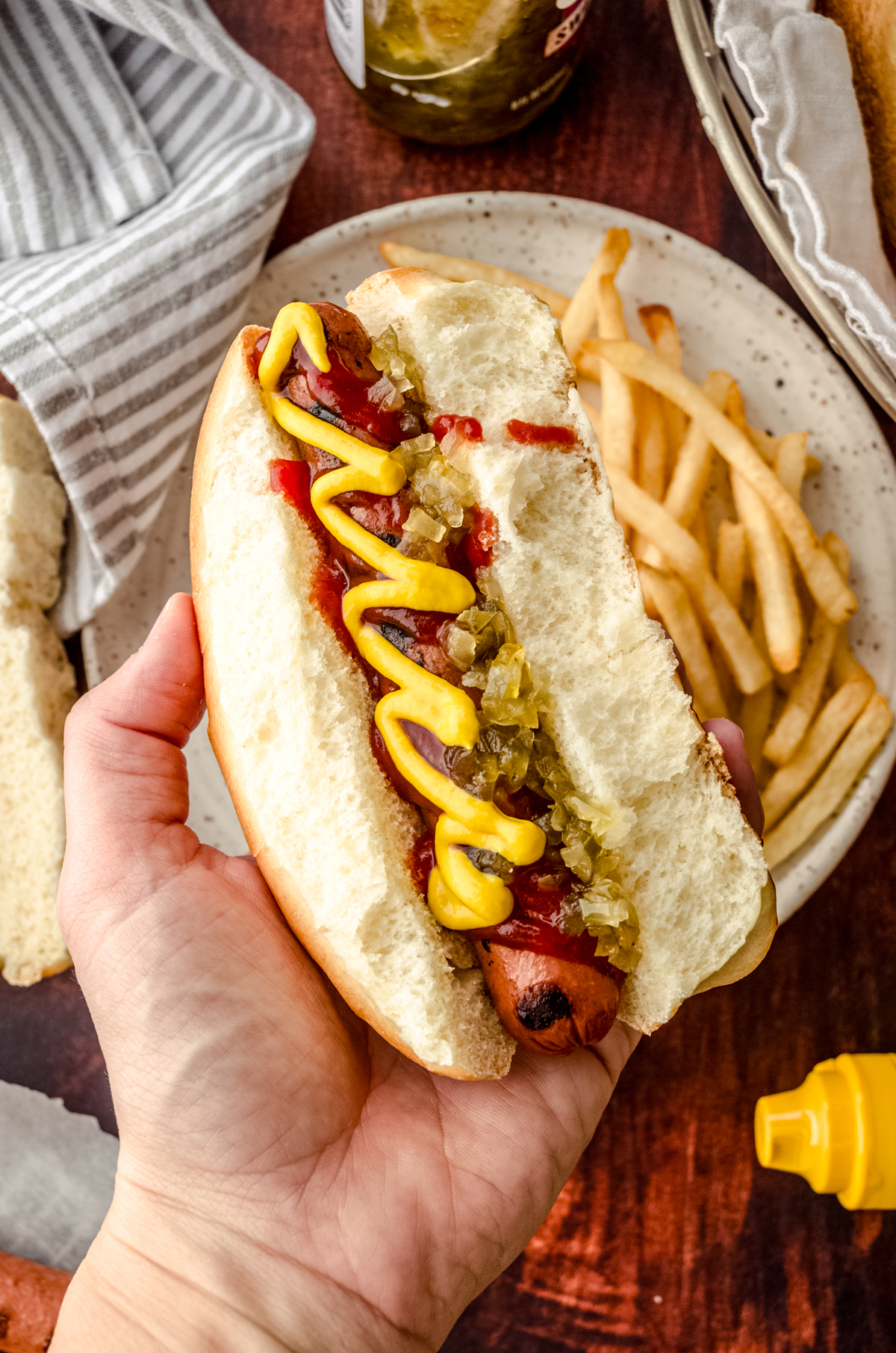 Aerial photo of someone holding a hot dog in a homemade hot dog bun.