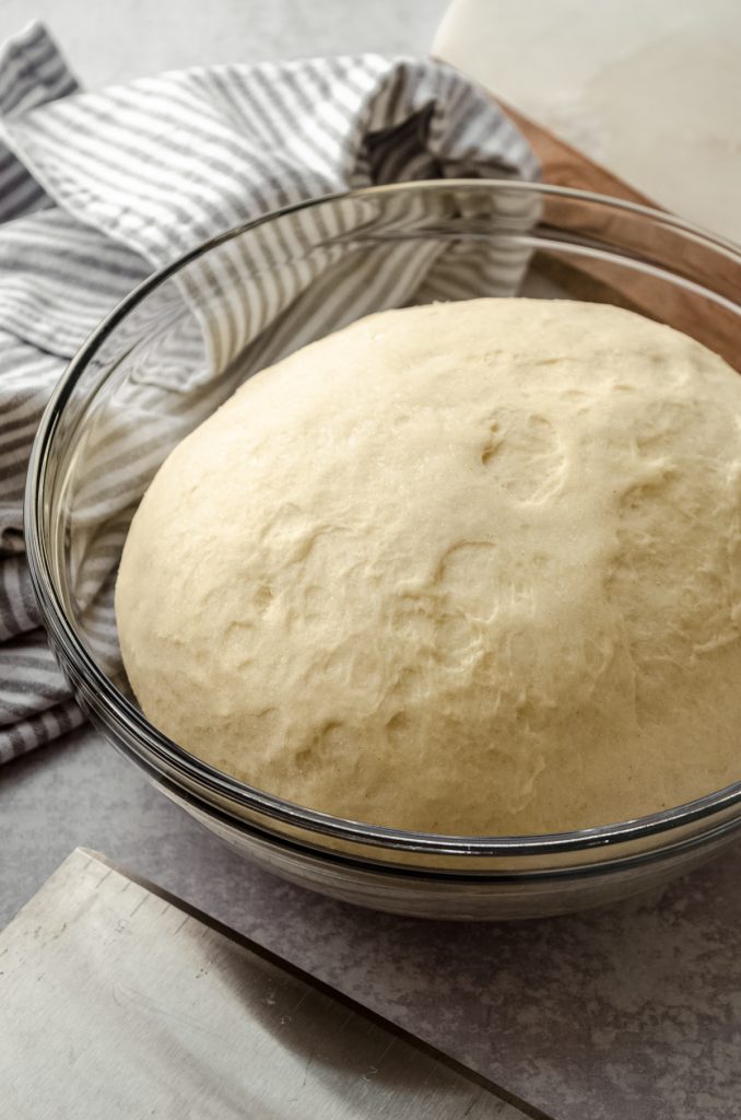 A bowl of yeast dough that has risen and is ready to punch down.