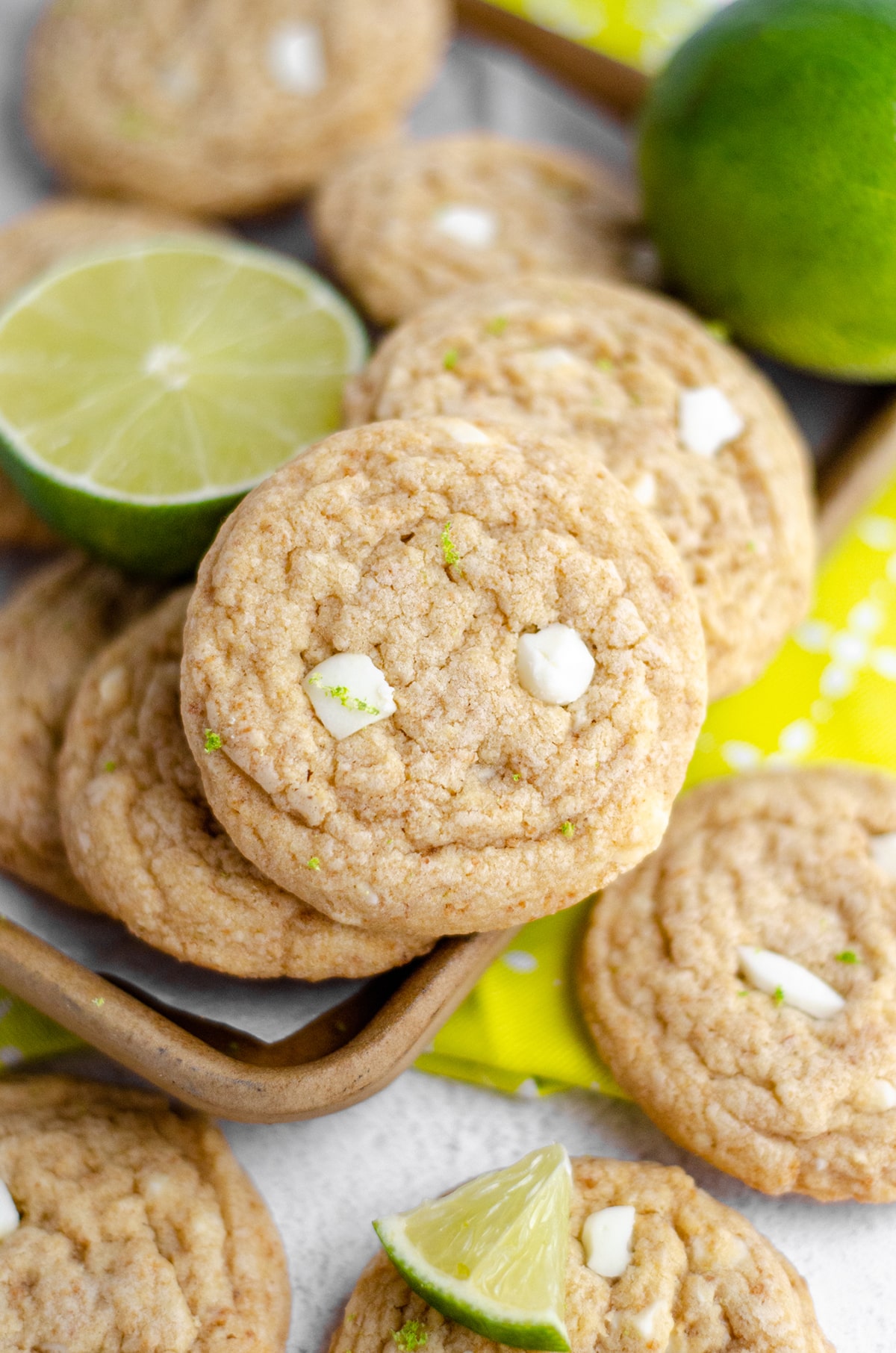 key lime cookies in a pile with fresh limes in the background