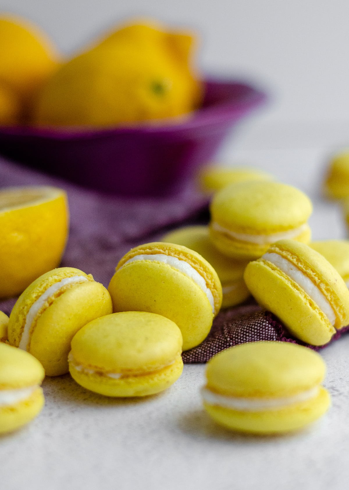 lemon macarons scattered around on a purple kitchen towel