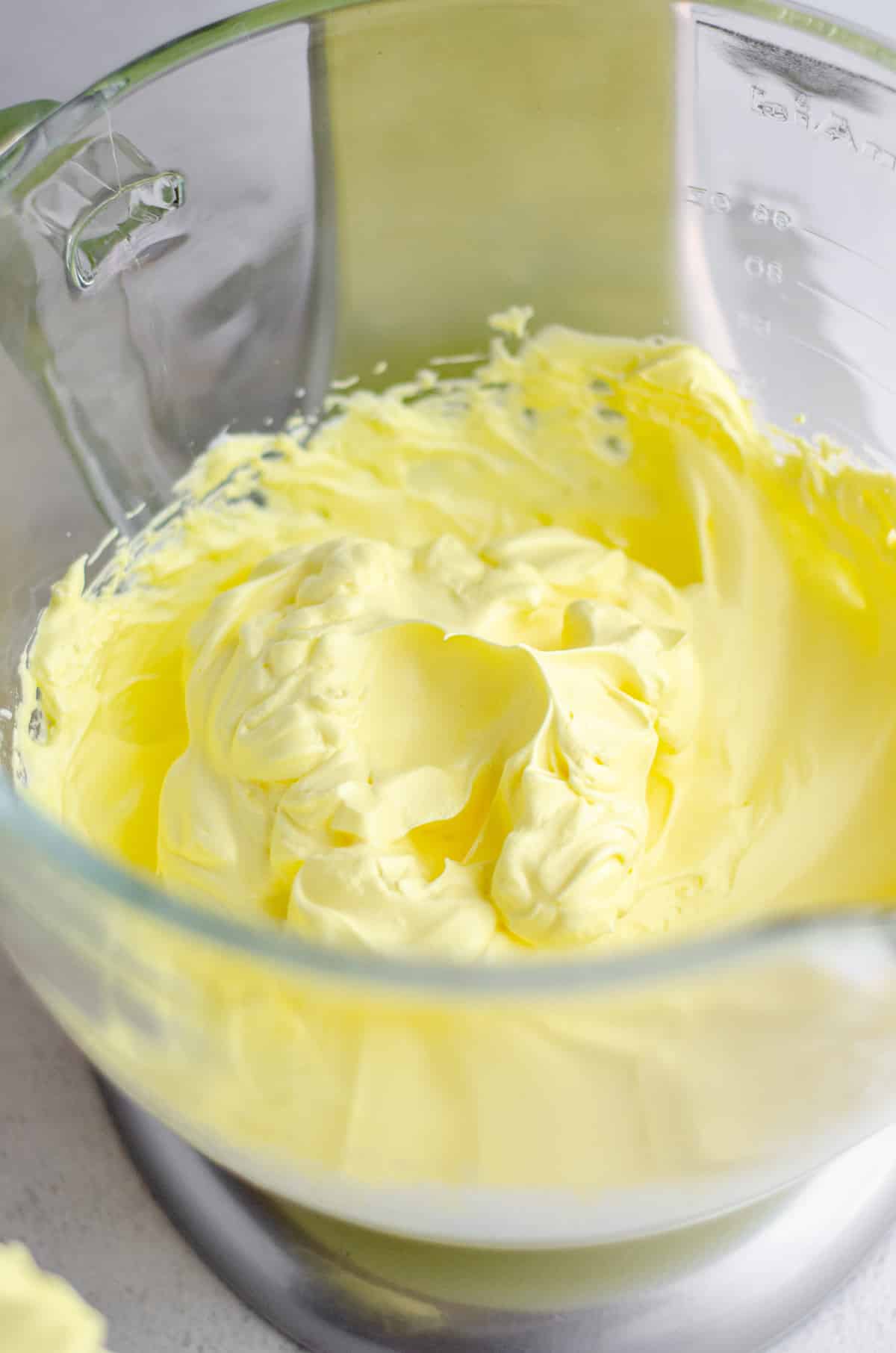 lemon macaron whipped egg whites in a glass bowl ready for macaronage