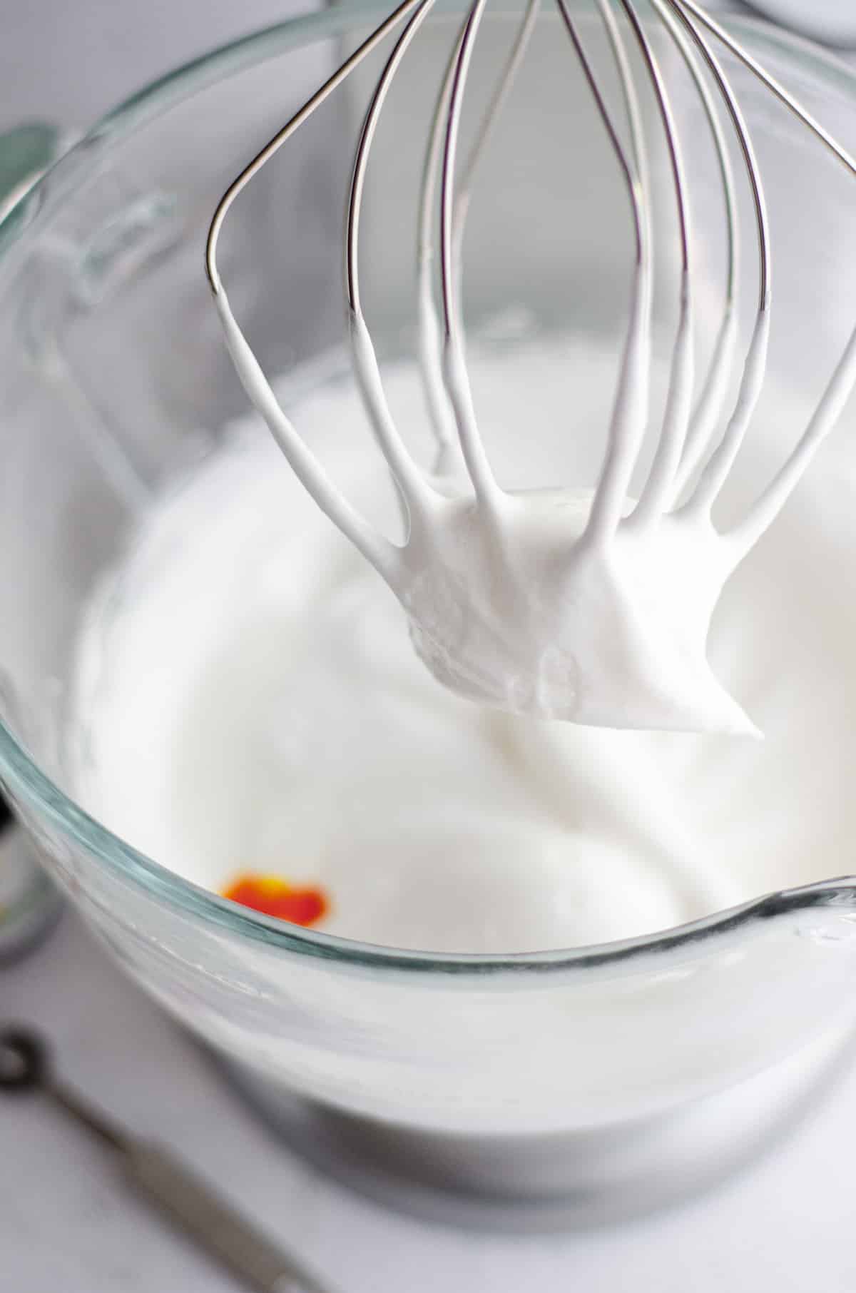 medium peaks on the tip of a whisk attachment for a stand mixer ready to make macarons