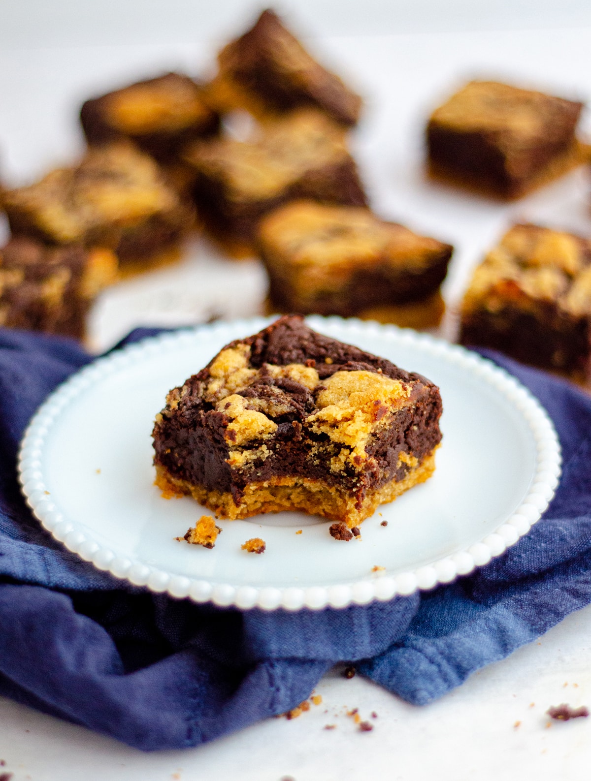 peanut butter cookie brownie sitting on a plate with a bite taken out of it and more brownies in the background