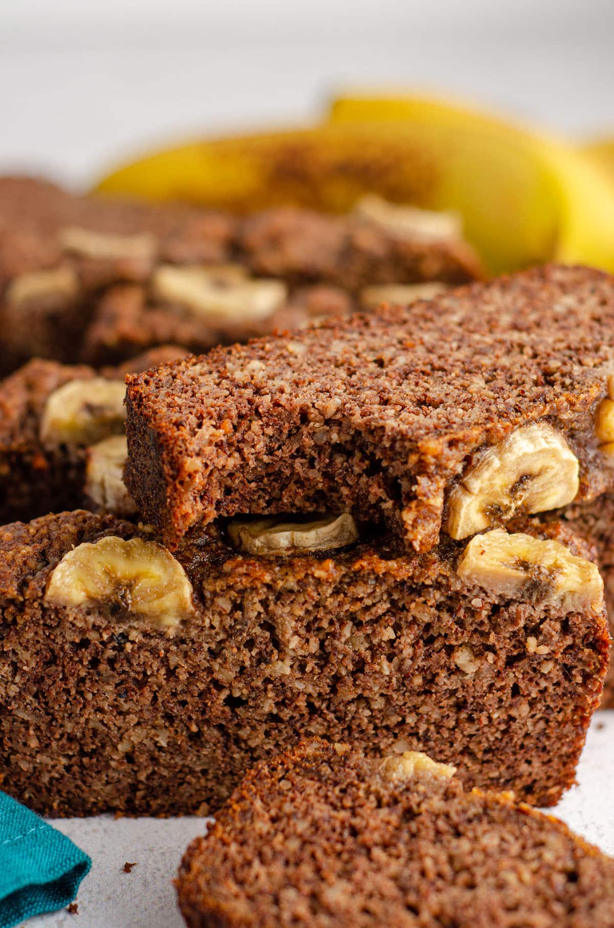 stack of almond flour banana bread slices with a bite taken out of the slice on top 