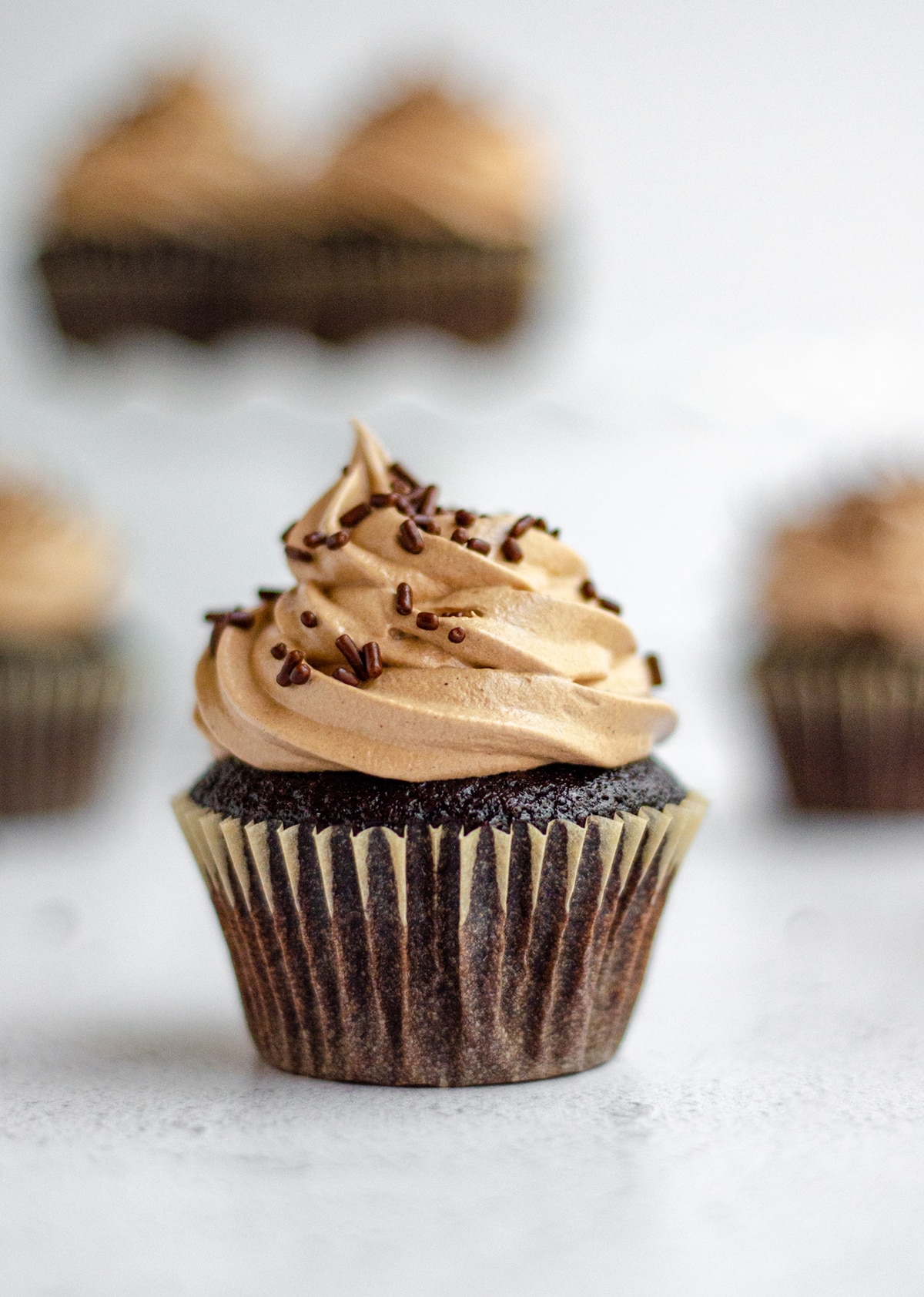 simple chocolate cupcakes with chocolate swiss meringue buttercream and chocolate sprinkles on top