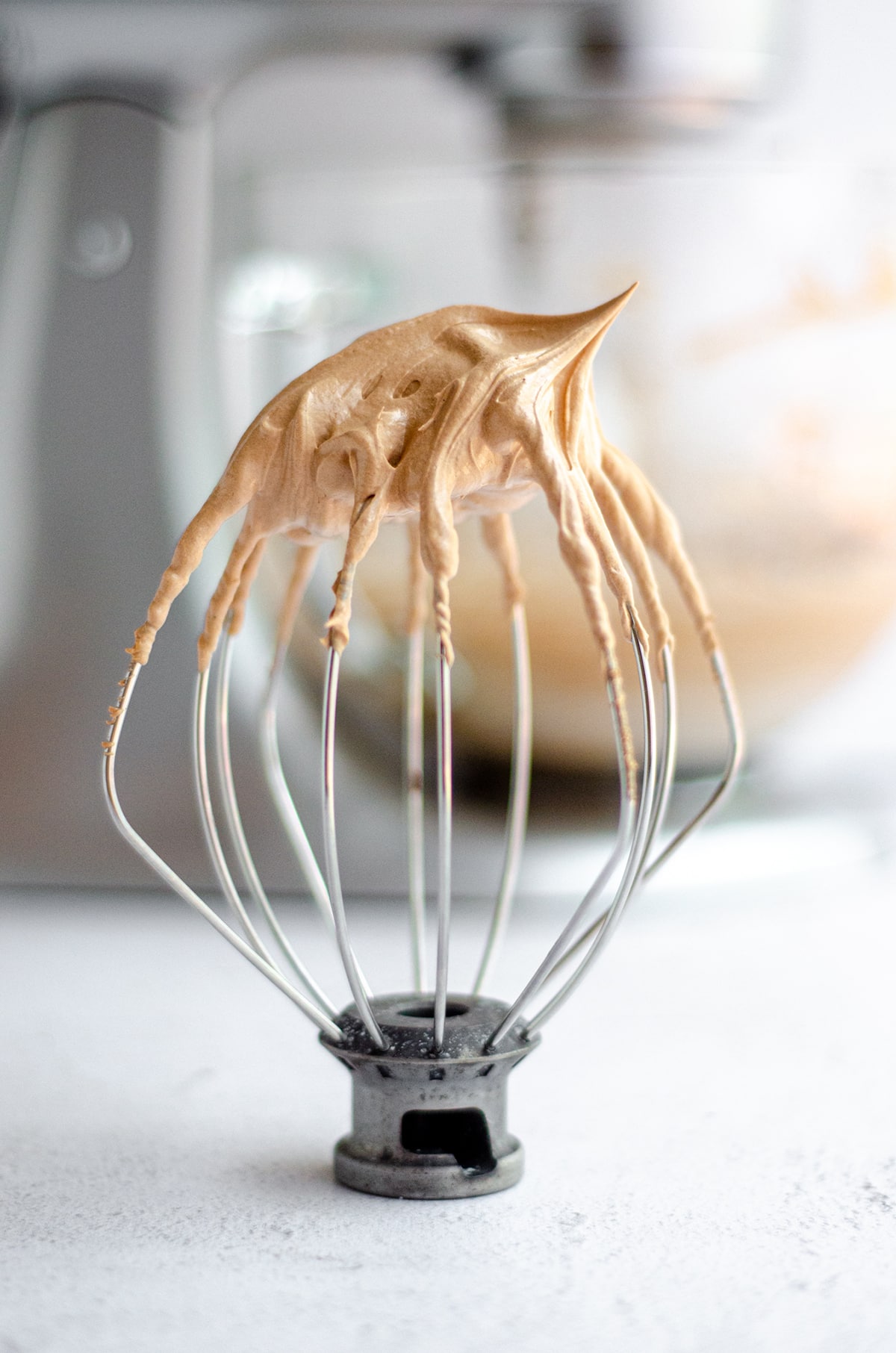 whisk attachment for a stand mixer with chocolate swiss meringue buttercream peaks on the tip