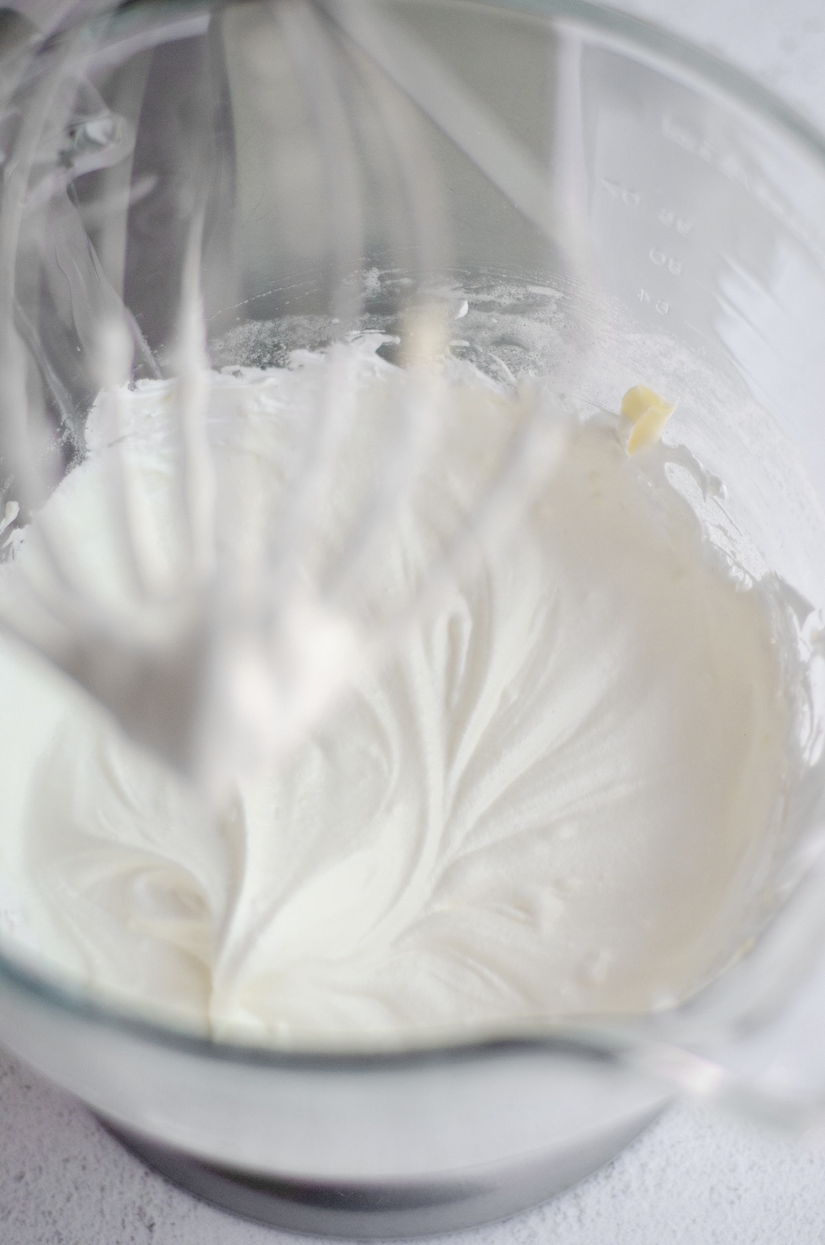 whipped egg whites in the bowl of a mixer with butter added in on its way to making swiss meringue buttercream