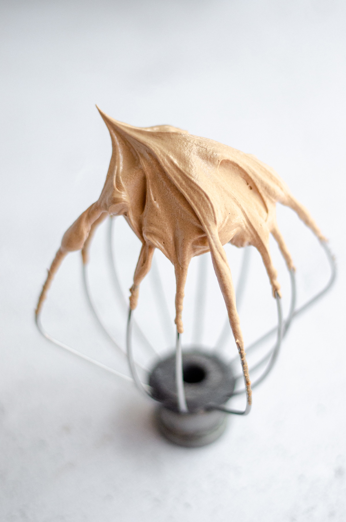 whisk attachment for a stand mixer with chocolate swiss meringue buttercream peaks on the tip
