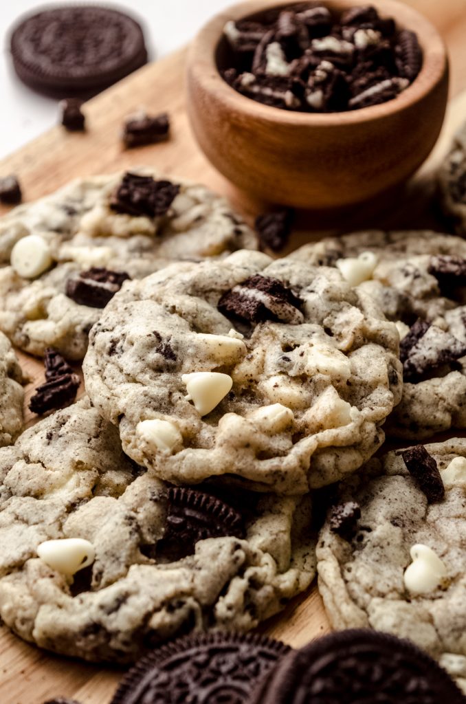 Cookies and cream cookies on a surface with a small bowl of crushed Oreos.