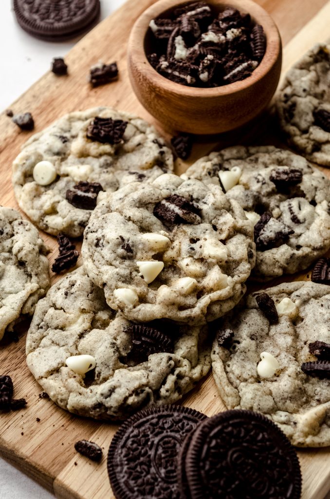 Cookies and cream cookies on a surface with a small bowl of crushed Oreos.