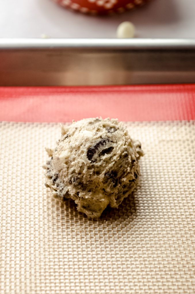 A ball of cookies and cream cookie dough on a baking sheet.