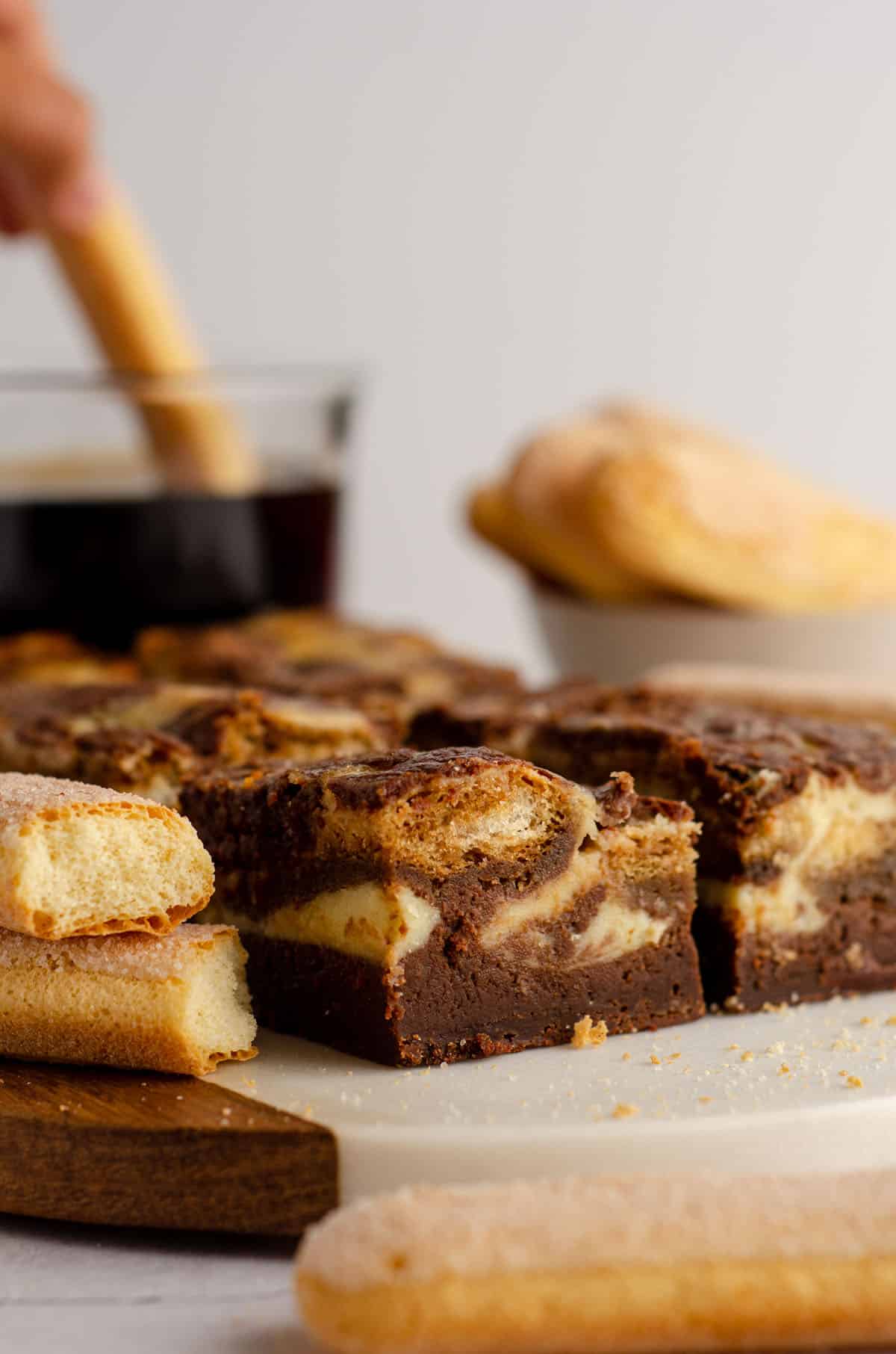 tiramisu brownies on a platter with coffee and ladyfingers in the background