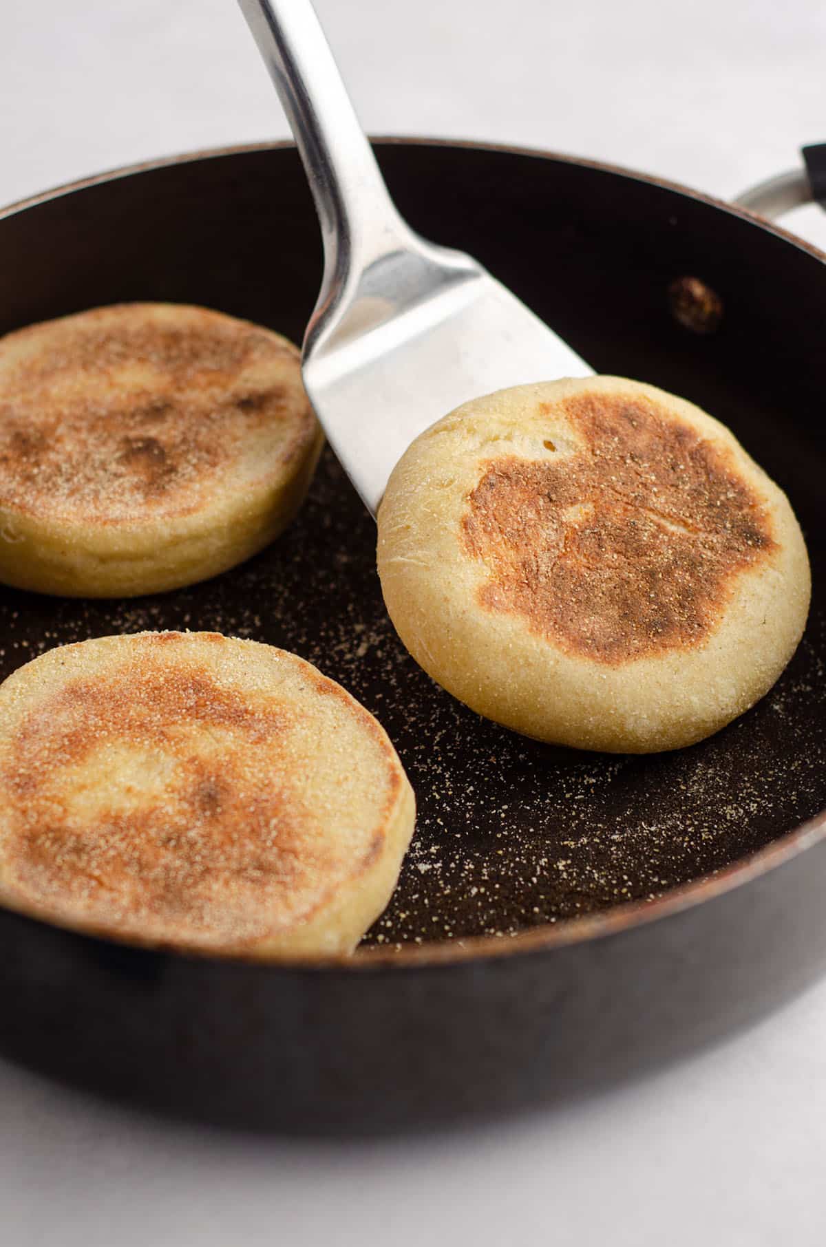 spatula flipping over a sourdough english muffin in a skillet