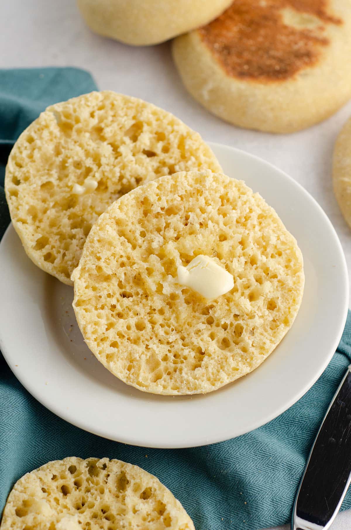 sourdough english muffin cut and on a white plate with butter melting on it