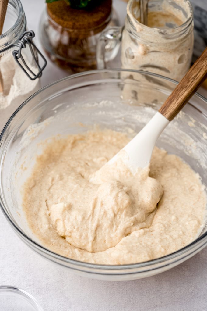 A bowl of sourdough cinnamon roll dough coming together in a bowl with a spatula.